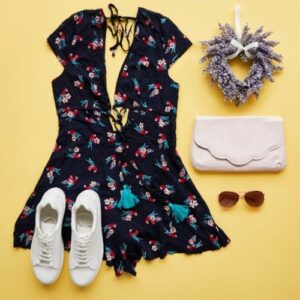 Flat photography of a black dress, white shoes, and accessories against a yellow background.