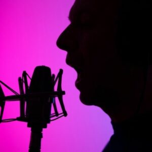 black silhouette of a man yelling into a studio microphone. 